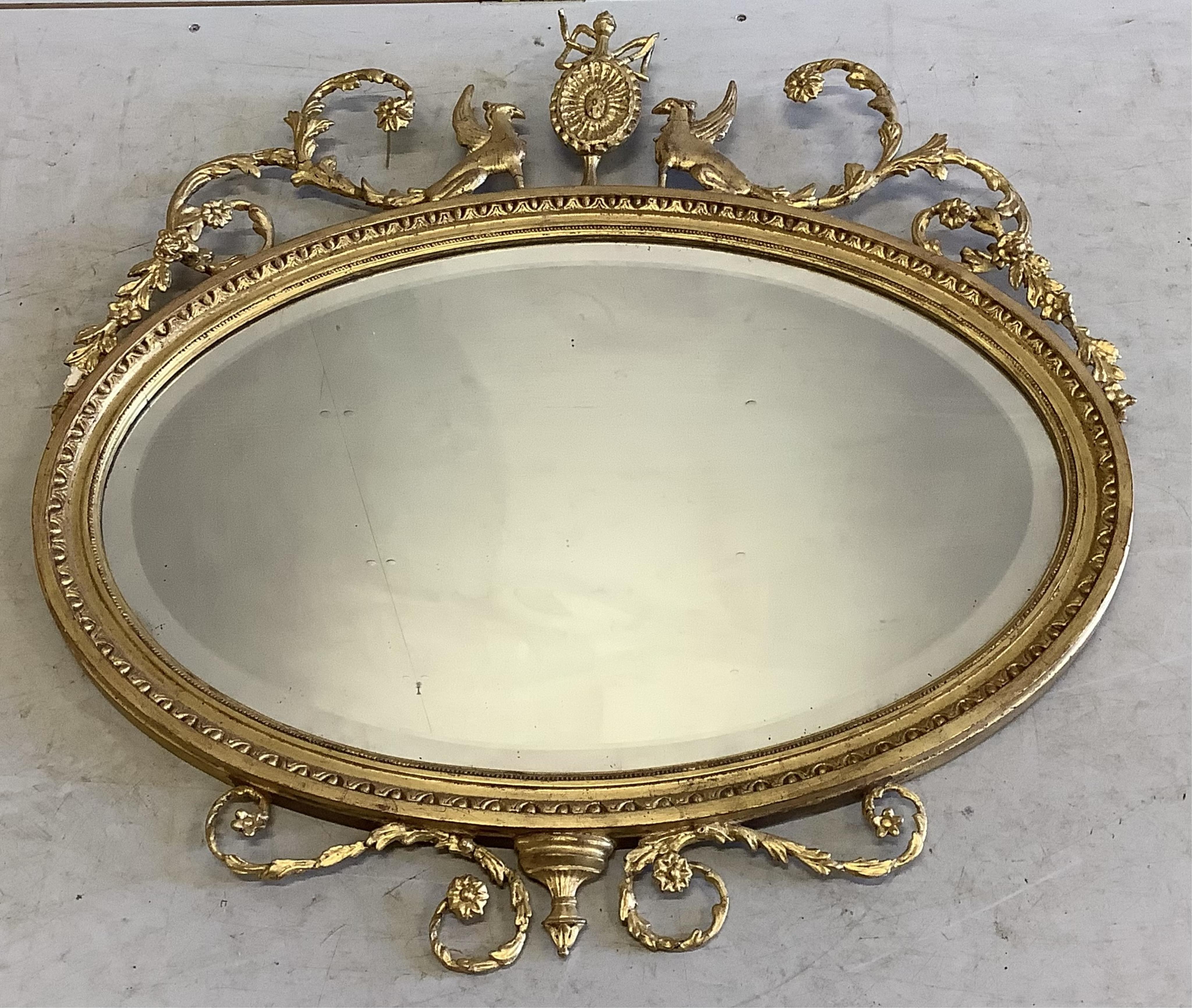 An Edwardian Sheraton Revival oval giltwood and composition wall mirror, width 86cm, height 90cm. Condition - fair